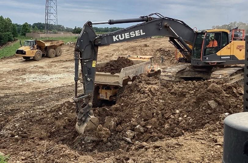 Excavator and dump truck team supporting utility excavation work