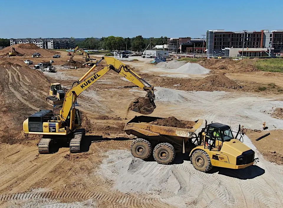 Kuesel excavator loading an articulated dump truck on an active earthworks jobsite