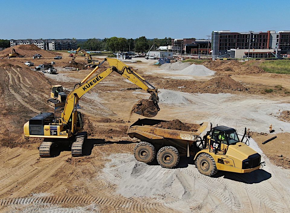 Kuesel excavator loading an articulated dump truck on an active earthworks jobsite